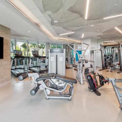 a fitness center with exercise equipment and a wall mounted tv
